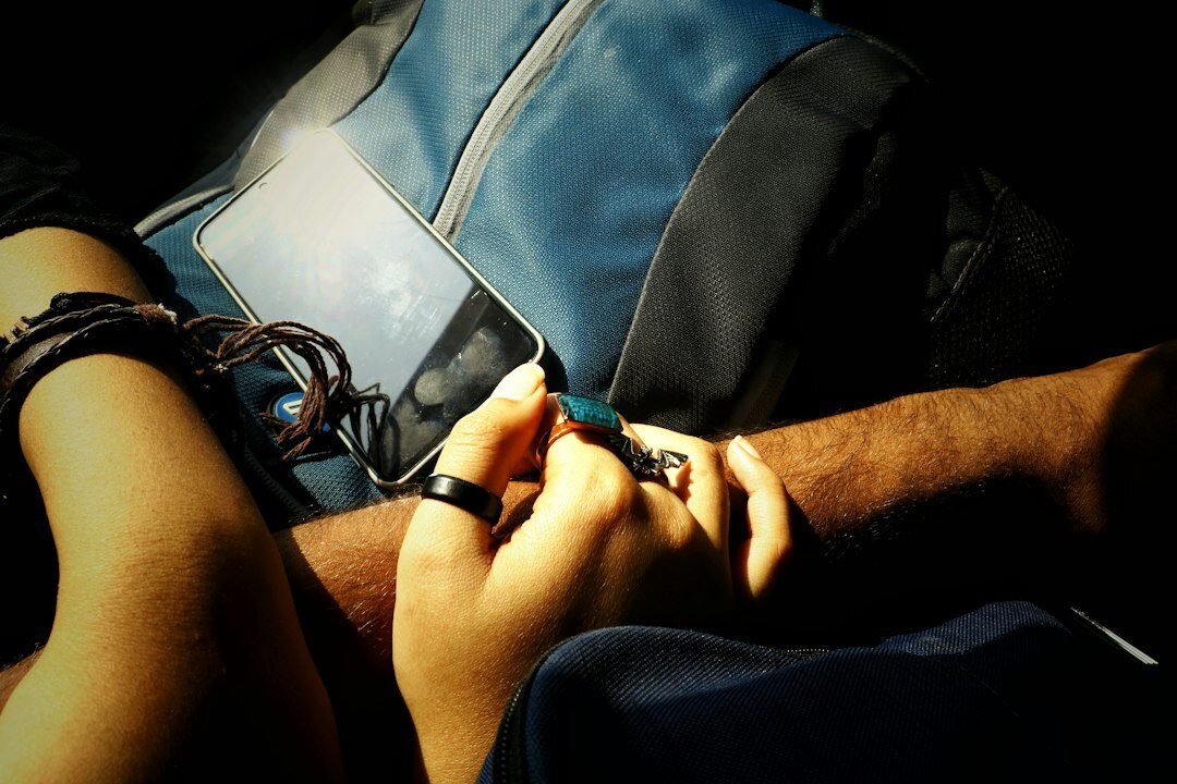 Close-up of hands writing notes and typing on a laptop at a wooden desk